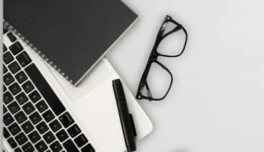 Notebook, glasses and laptop on a desk